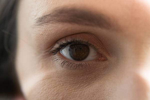 Close-up of a brown eye and eyebrow, highlighting skin texture and fine lines.