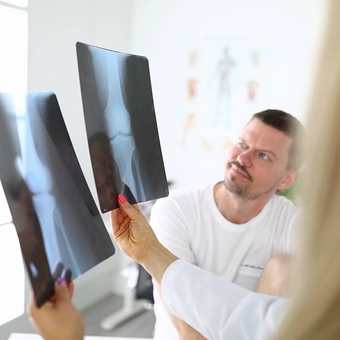 A doctor reviews two knee X-rays with a man, talking about natural joint pain relief supplements.