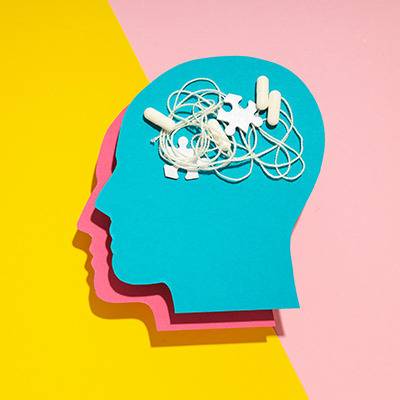 A blue paper cutout head on a pink and yellow background with puzzle pieces inside, symbolizing confusion about pain relief.