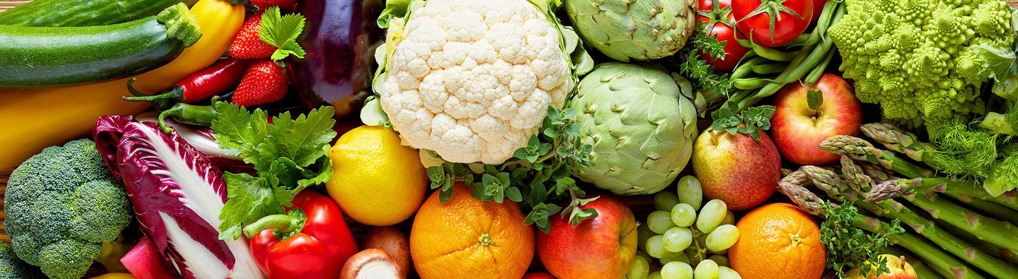 Fresh fruits and vegetables including cauliflower, apples, citrus, grapes, and leafy greens displayed together.