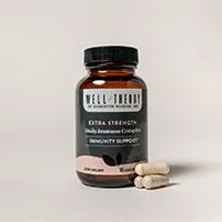 Brown bottle labeled "Well Theory Extra Strength Immunity Support" and two white capsules on a plain background.