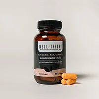 A brown "Well Theory Joint Health Multi" bottle with yellow capsules beside it on a plain background.