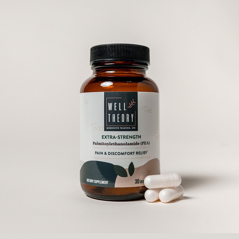 A brown "Well Theory Extra-Strength PEA" bottle sits by four white capsules on a light background.