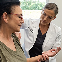 A healthcare professional examines a woman's wrist while discussing natural pain relief supplements.