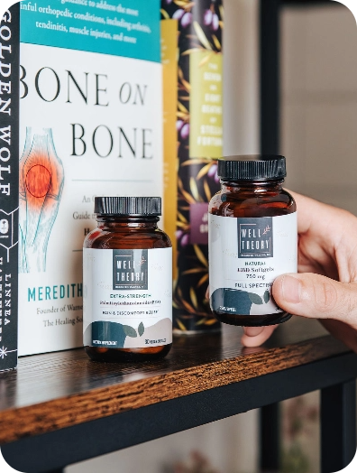 Two supplement bottles by books, including "Bone on Bone," as a hand gently touches one bottle.